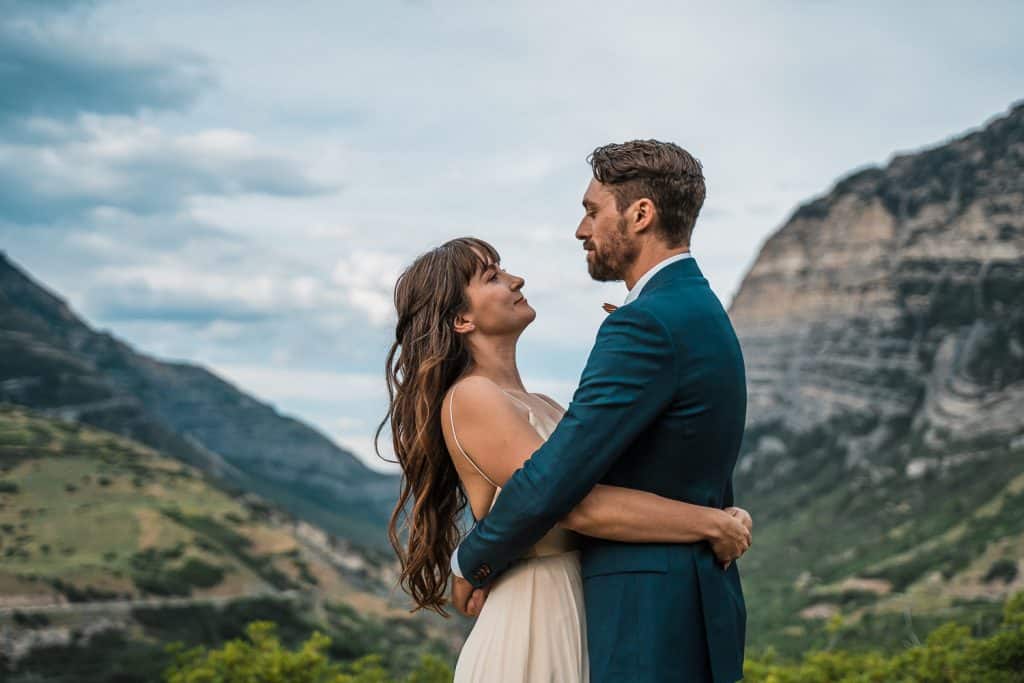 couple in the forefront of picture embracing with a view of Provo canyon Utah behind them