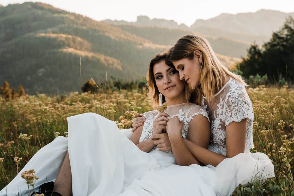 utah-mountain-lInspiration for an LGBTQ Adventure Elopement near Salt Lake City, Utah. Rian and Tearsha sitting in a field of wildflowers and holding each other close. gbtq-adventure-elopement