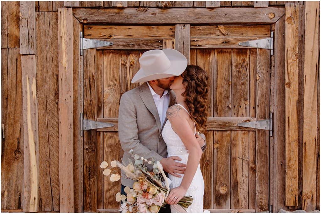bride and groom kissing in front of old barn