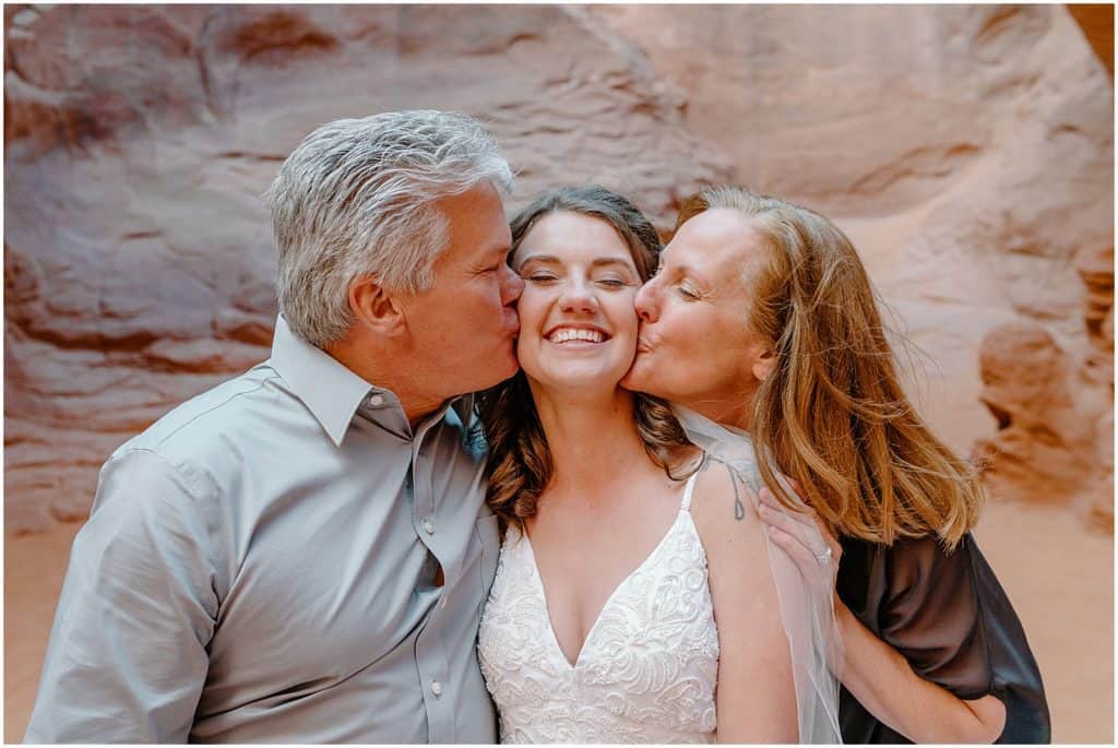 brides parents kissing her on the cheek 