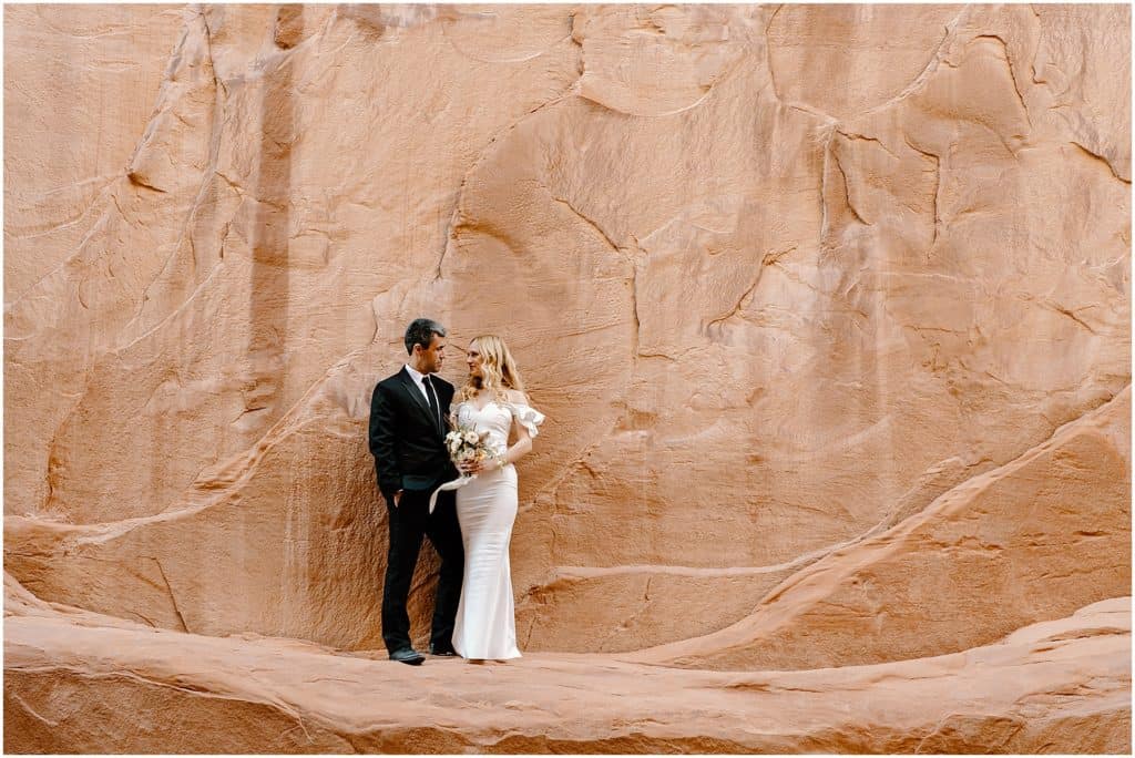 bride and groom in front of canyon rock wall in moab for their elopement.