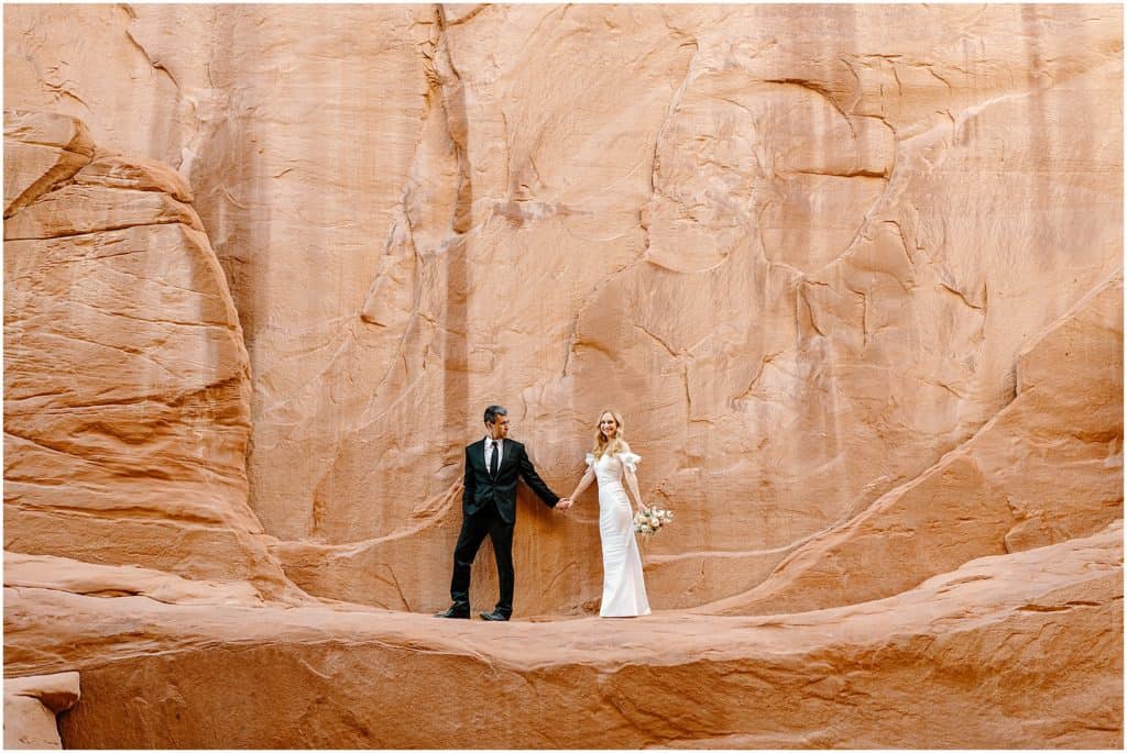bride and groom in front of canyon rock wall in moab.
