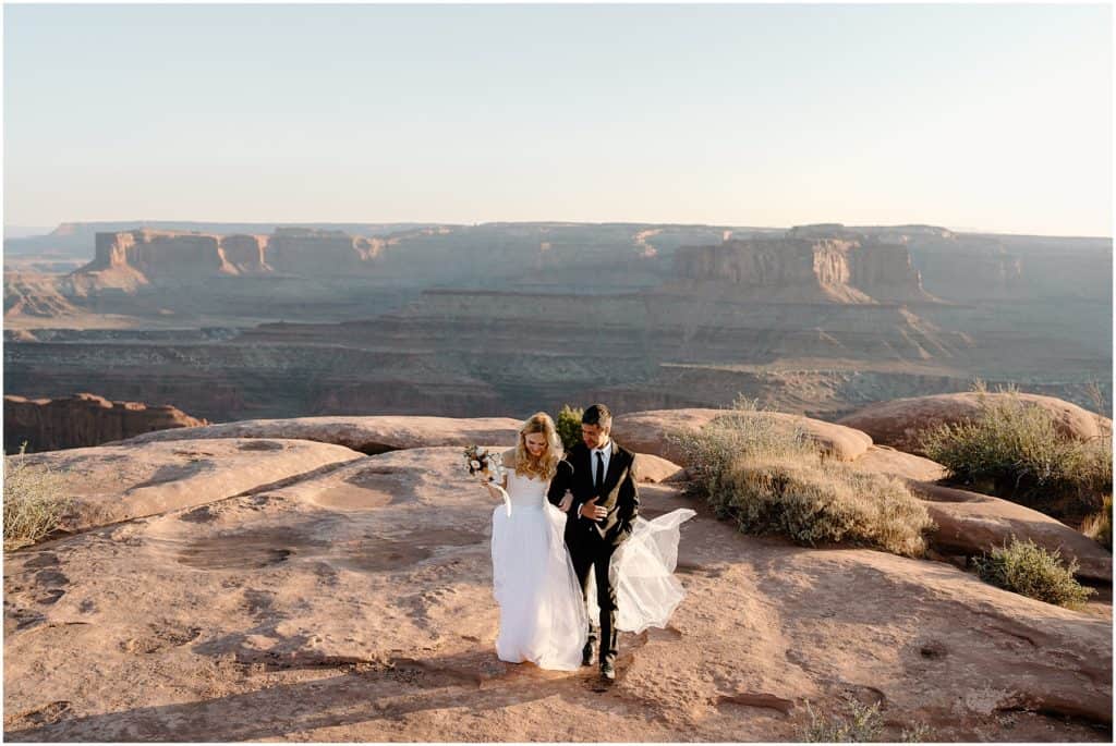 brides tulle skirt blowing in the wind behind the couple. with a view of the canyonlands national park in the background.