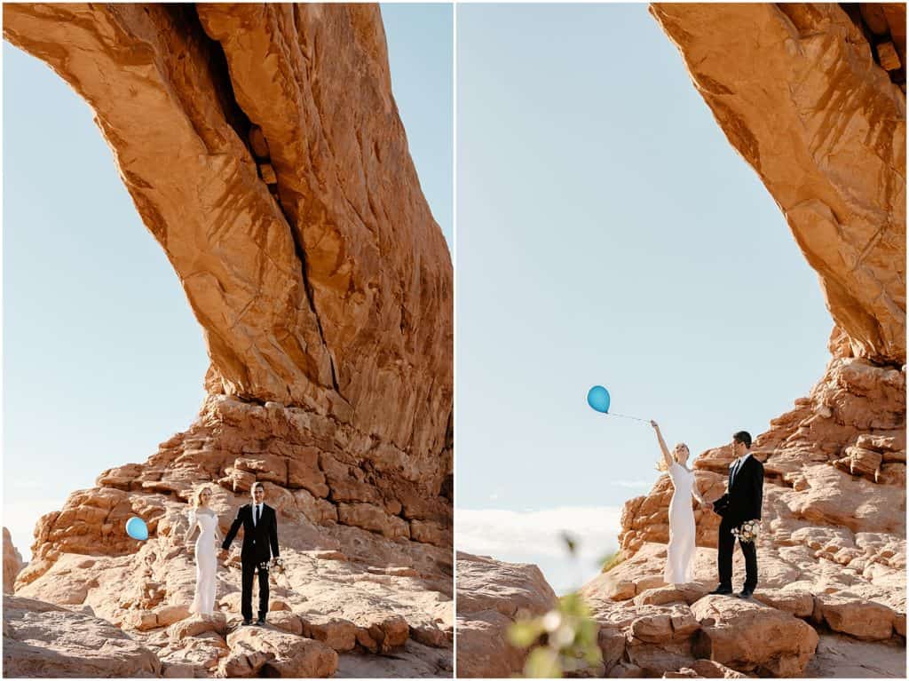 couple holding blue balloon. in an arch  in moab for their elopement.
