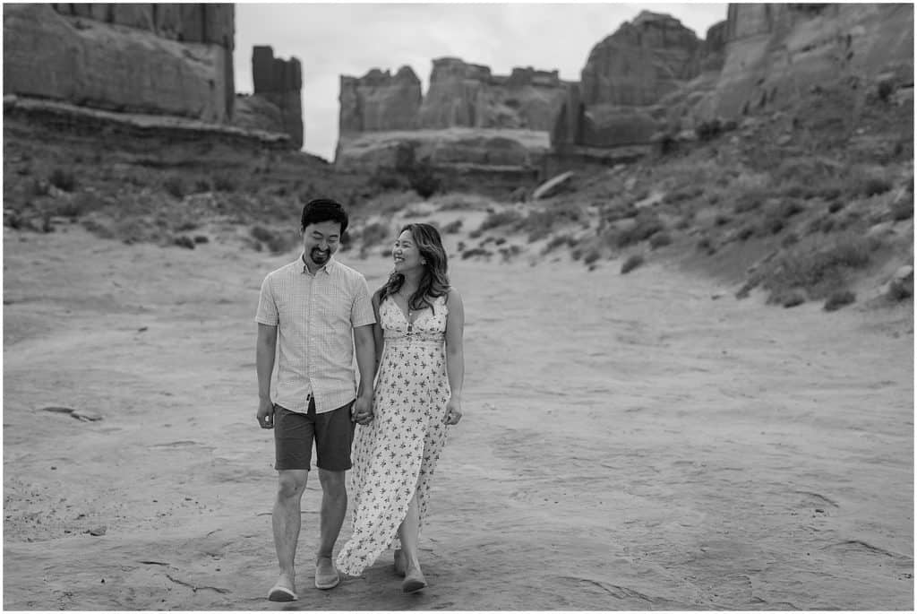 black and white shot of couple holding hands on their adventure session in the arches national park