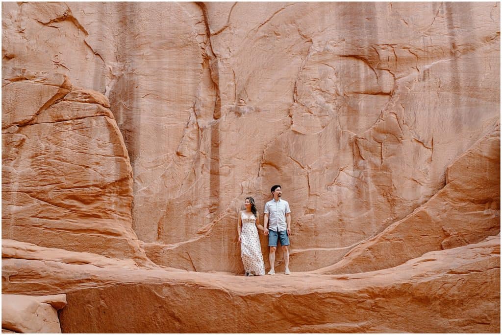 couple in front of rock wall in utah on their adventure session in the arches national park