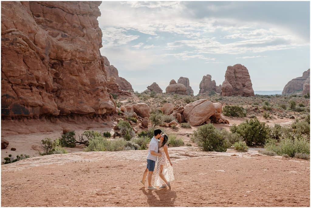 photo of couple kissing with the utah landscape behind them