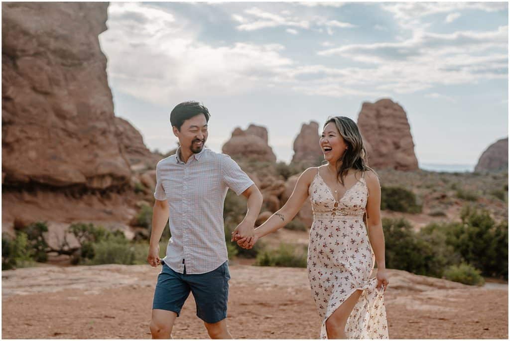 photo of couple holding hands and smiling on their adventure session in the arches national park