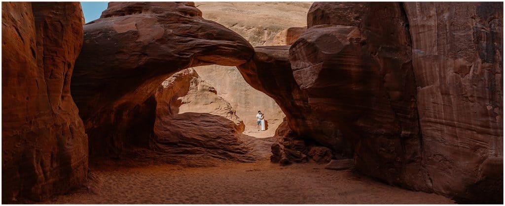 couple under arch in utah on their adventure session in the arches national park