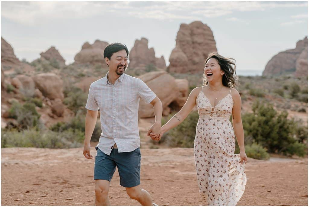 photo of couple holding hands and smiling on their adventure session in the arches national park