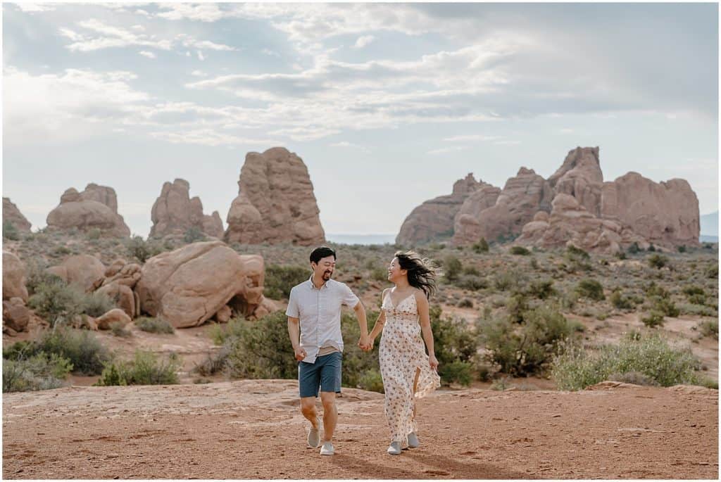 photo of couple holding hands and smiling on their adventure session in the arches national park