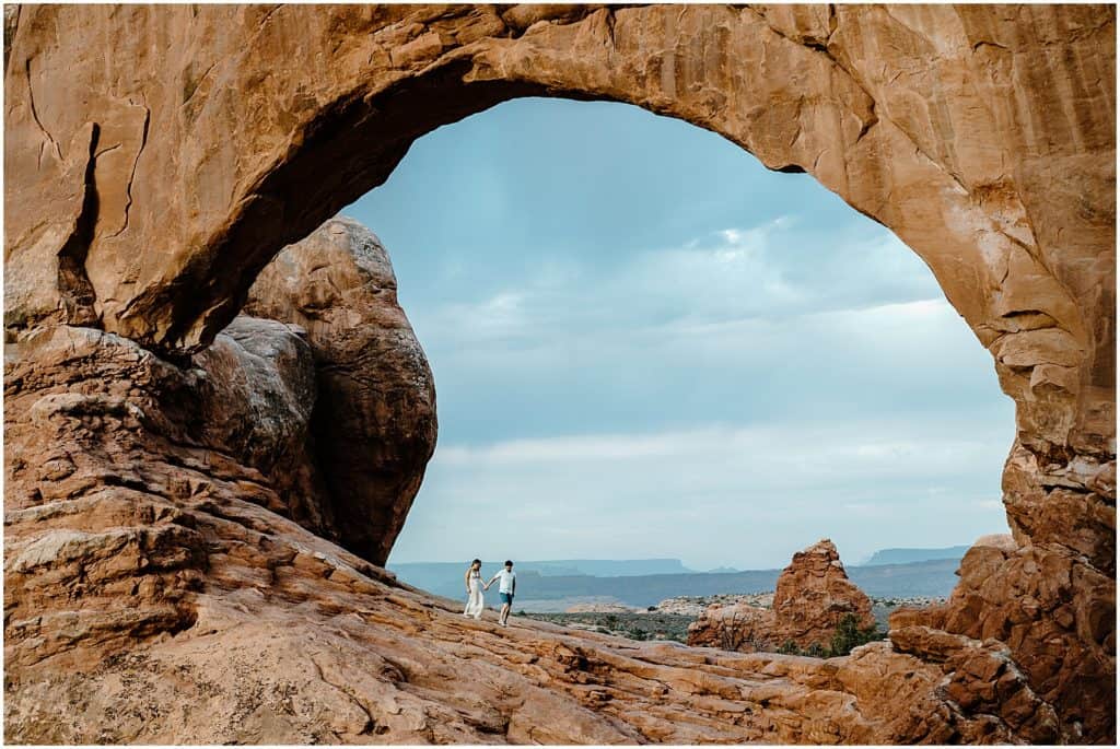 couple under arch in utah on their adventure session in the arches national park