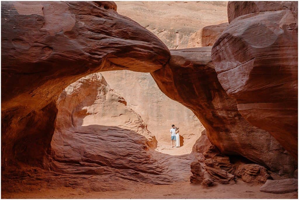 couple under arch in utah on their adventure session in the arches national park