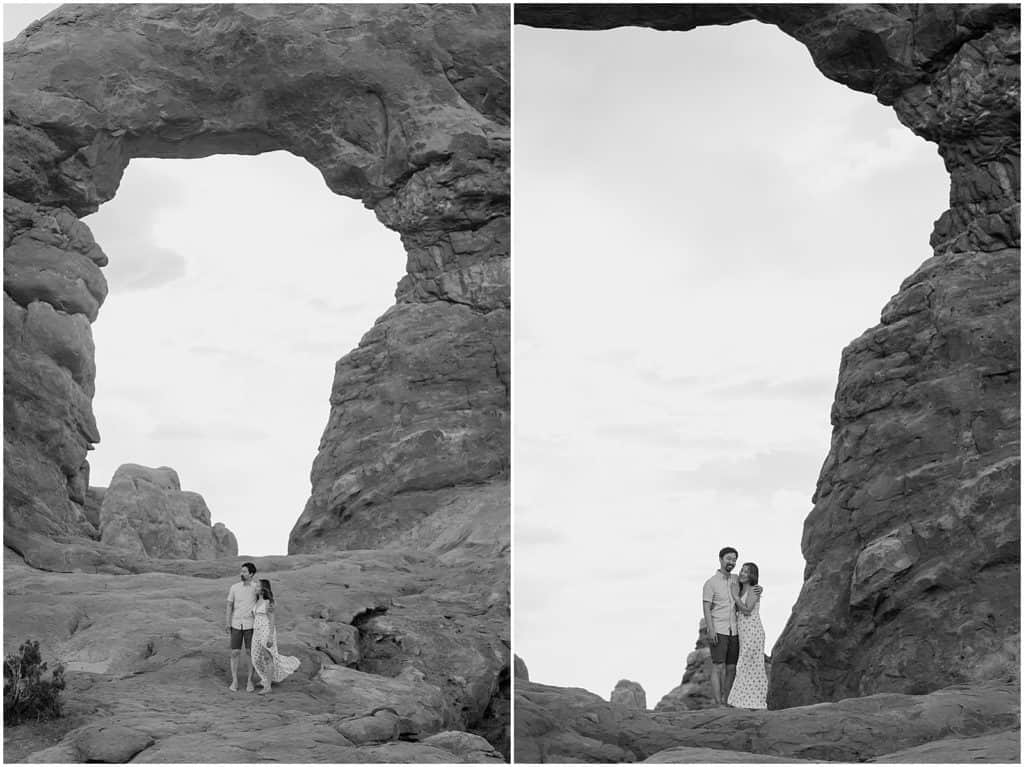 couple under slot canyon in utah on their adventure session in the arches national park in black and white