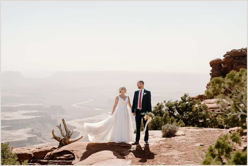 A bride and groom stand at the edge of Utah cliff after their Moab elopement ceremony. 