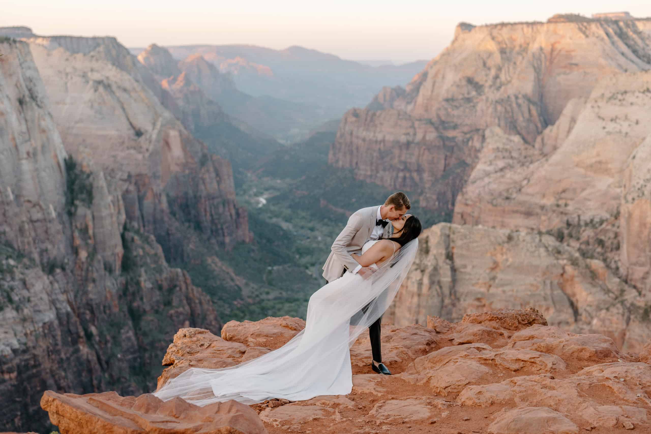 A couple kiss against the backdrop of a Yosemite National Park overview. Scenery like this is one of the reasons couples should consider eloping.