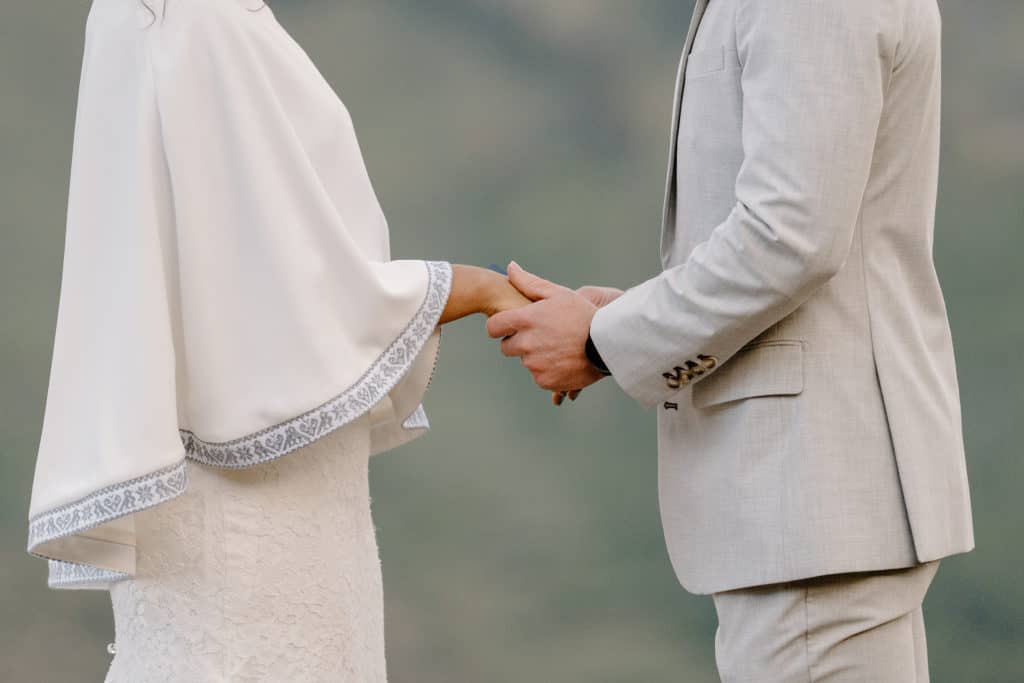 The bride and groom take hands during their Colorado elopement cermony. 