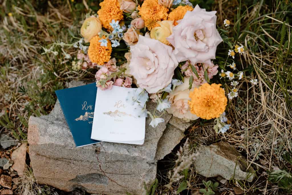 This image shows the bride and grooms vow books, their floral bouquet, and other details from their Colorado elopement ceremony. 