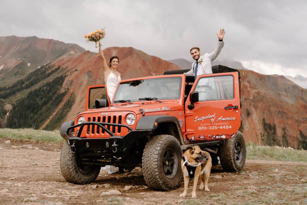 Ana and Greg raise their hands in celebration out of their Ouray jeep. The couple celebrates their Colorado adventure elopement high in the San Juan mountains. 