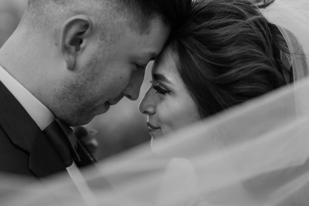 A bride leans her head in close to her groom during their adventure elopement ceremony. This elopement photo is in black and white. 