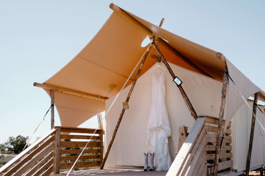 A wedding gown hangs in a billowing white tent at Under Canvas Moab, where the bride and groom stayed for their Southern Utah wedding.