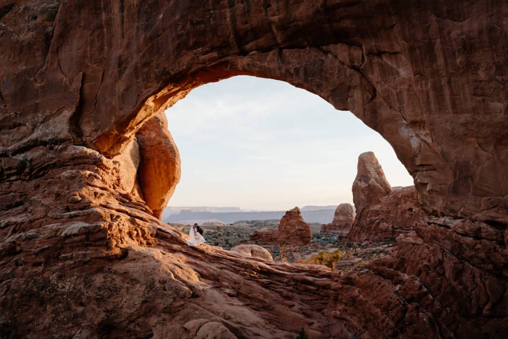 A bride and groom adventure across an ancient arch in Moab, Utah for their Southern Utah elopement ceremony. 