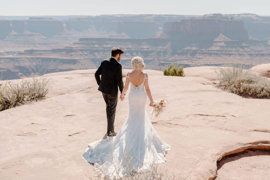 A couple walks toward the overlook at a Southern Utah vista during their elopement ceremony in a Utah state park.
