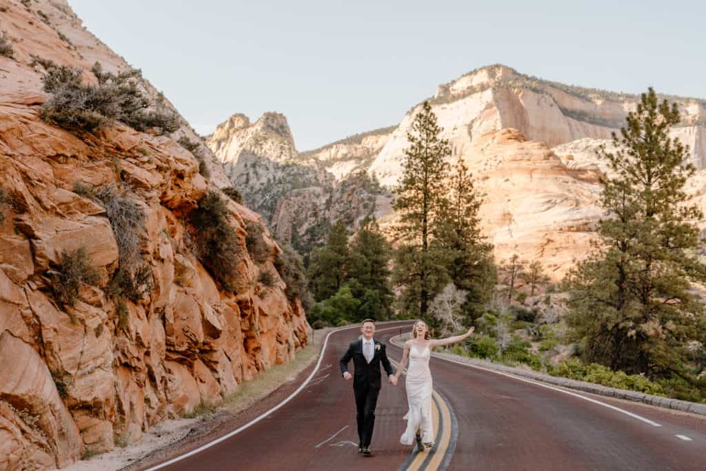 A groom and a bride hold hands as they stroll down the streets of Zion after their Utah adventure elopement ceremony. 