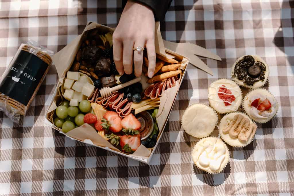 A bride reaches for her charcuterie board during her Zion National Park elopement picnic. 