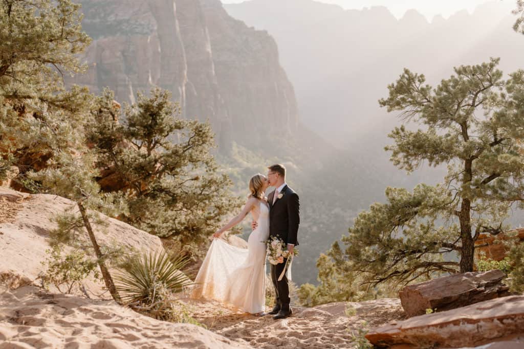 A bride and groom kiss and embrace at Overlook Trail in Zion during their Zion National Park elopement. 