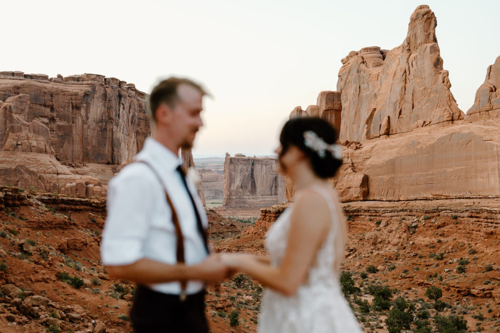 A couple holds each other close amid the backdrop of the jagged rocks and red clay features of Southern Utah, a spot their elopement wedding coordinator helped them choose. 