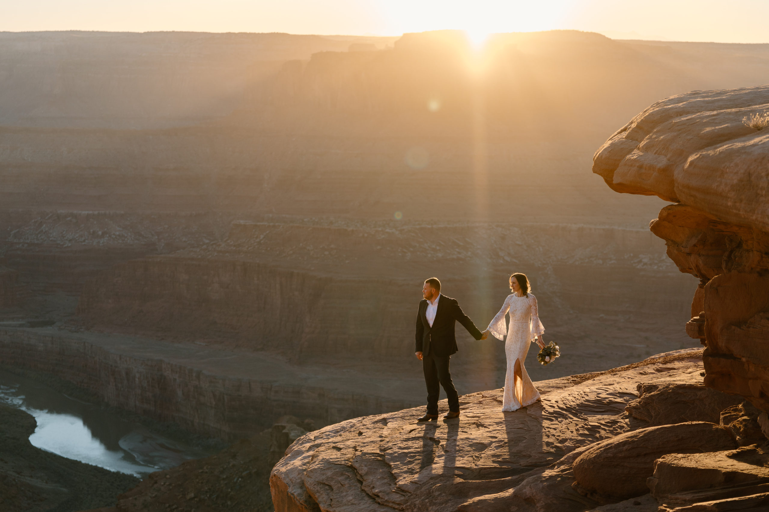An eloping couple look out on the cliff sides of Utah, a spot their elopement photographer found and their wedding coordinator made happen.