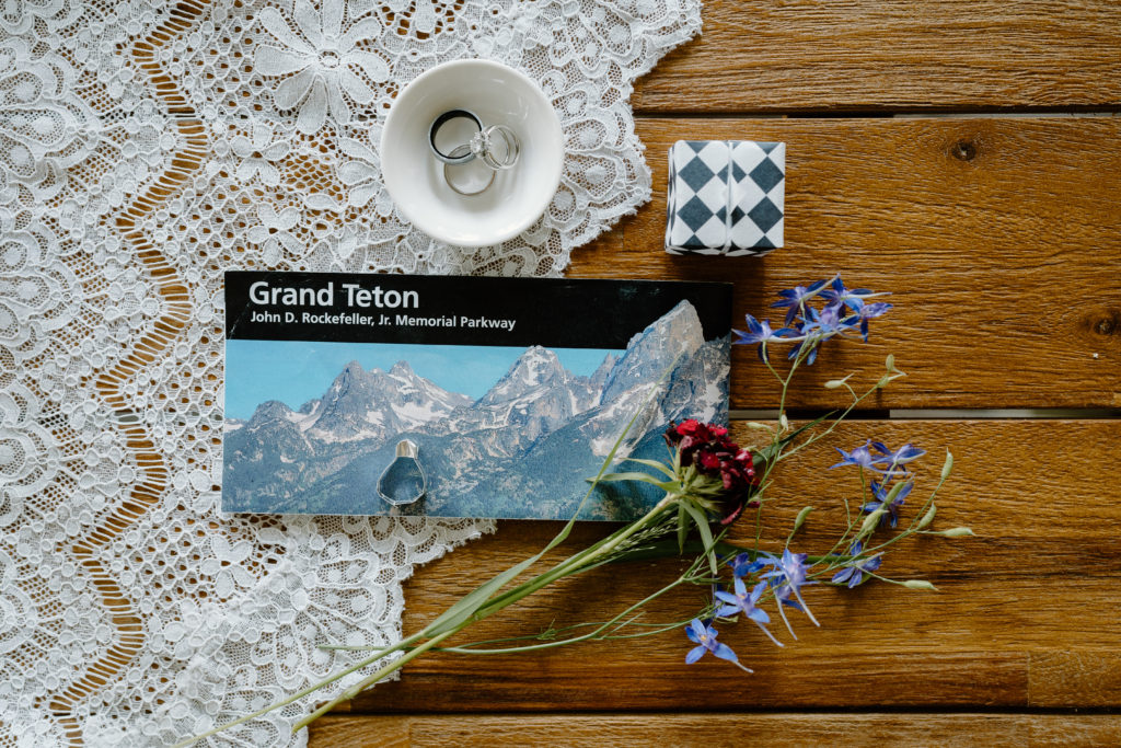 Details of a couple's Grand Teton National park elopement day is shown here on a wooden table. 