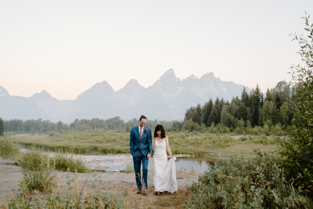 A bride and groom walk along the edge of the Grand Teton National Park during their elopement.  
