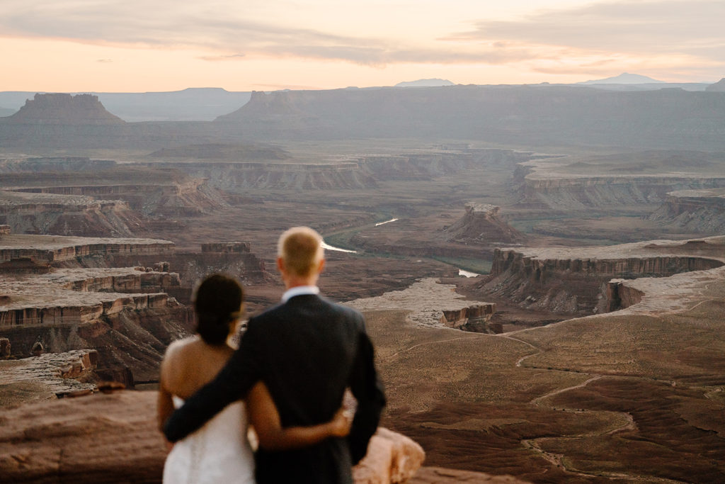 A bride and groom stare out over a beautiful sunset, something they wanted to make sure they included in their Utah elopement timeline. 