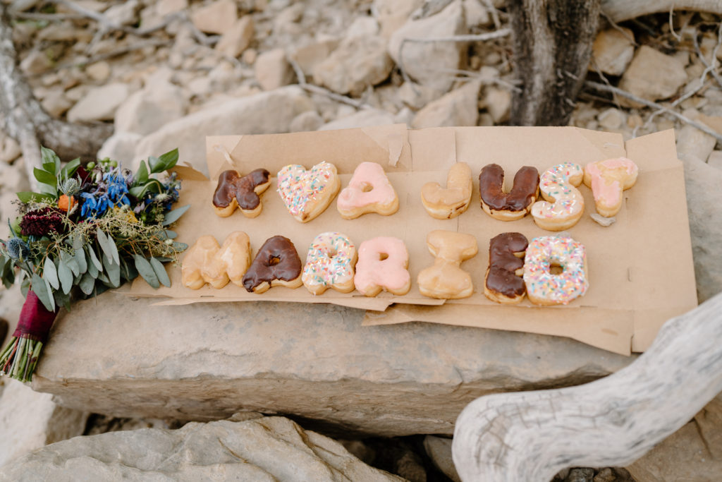 A donut display spells out "Just Married" to celebrate a couple's Moab rafting elopement in Utah. 