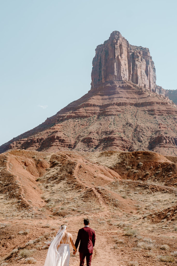 A bride and groom hike up a gorgeous, southwest trail in Southern Utah during their elopement ceremony, something they made sure to include in their elopement timeline. 