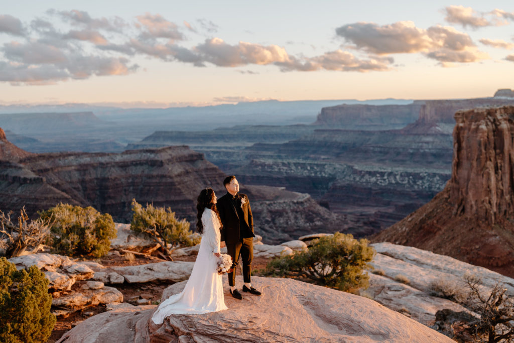 A couple looks out onto the setting sun on the desert during their Moab adventure elopement.