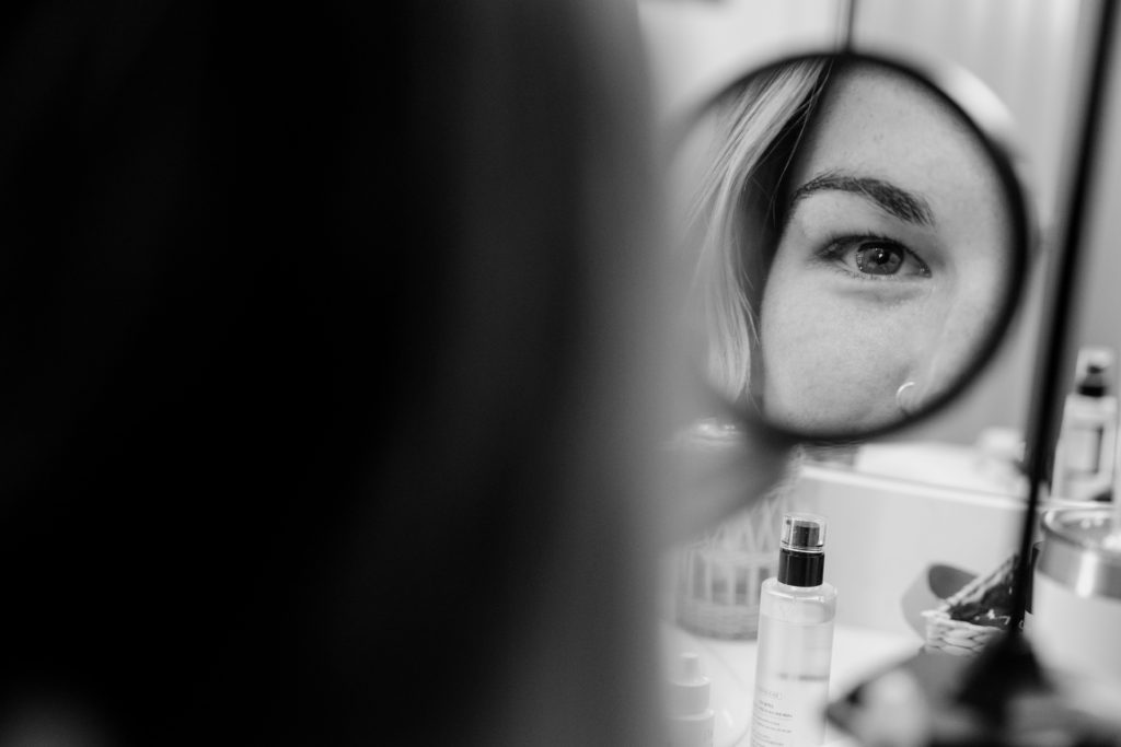 A bride looks in the mirror as she gets ready for her epic elopement dya. 
