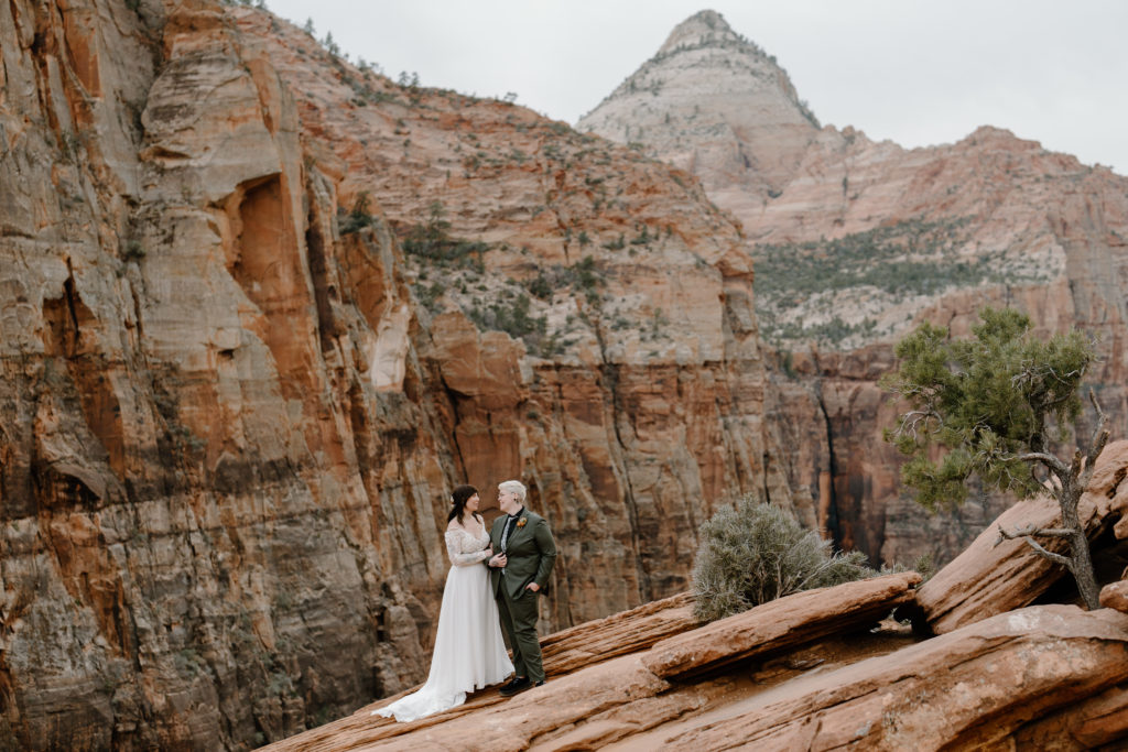 A young couple stands among the arches and sandstone, experiencing their southern Utah adventure elopement.