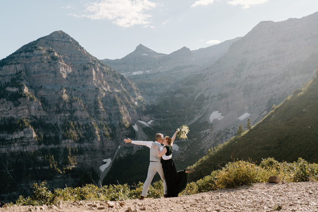 A husband and wife pose in a silly way overlooking a Salt Lake City valley