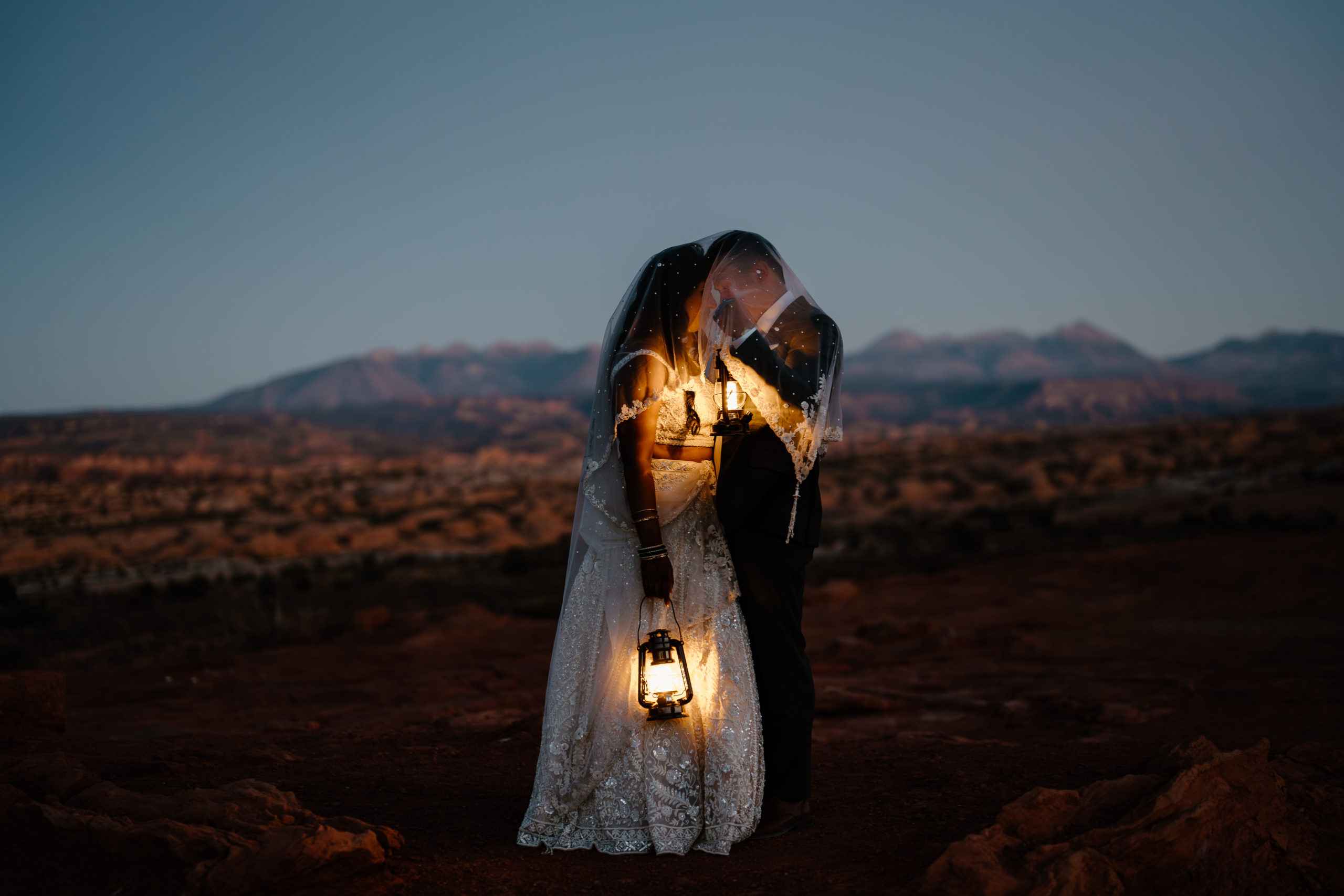 A couple explores Moab Utah by lantern light during their all-day elopement.