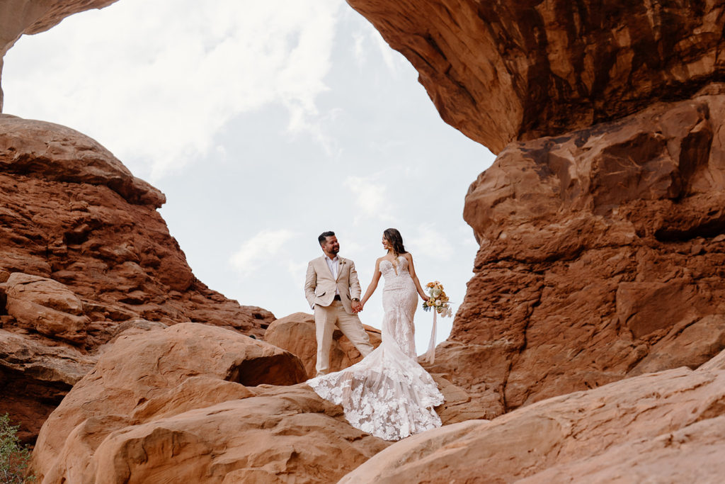 A bride and groom stand in the middle of Arches National park during their all-day elopement. 