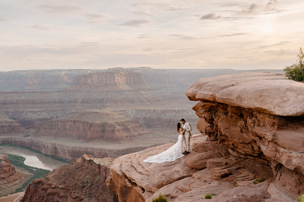 A bride and groom hold eachother close while they pose on the cliff in a Utah desert during their two-day elopement.
