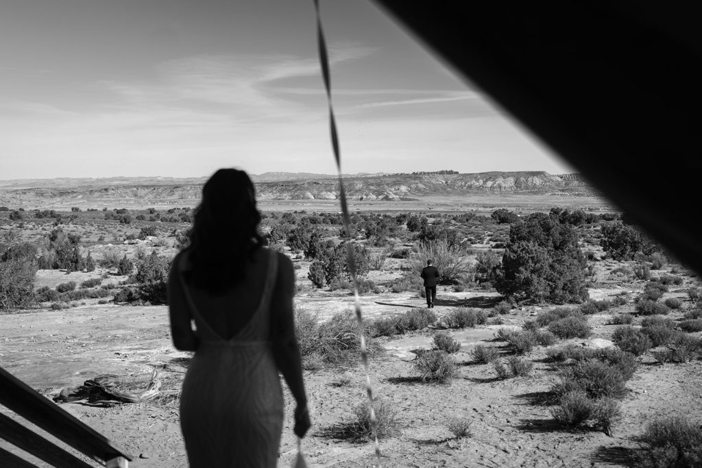 A bride looks out over the Utah desert at her groom for the first look during their two-day elopement package.
